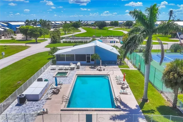 a view of a swimming pool and lounge chairs in back yard of the house