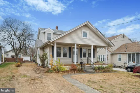 a view of a white house with a large tree in front of it