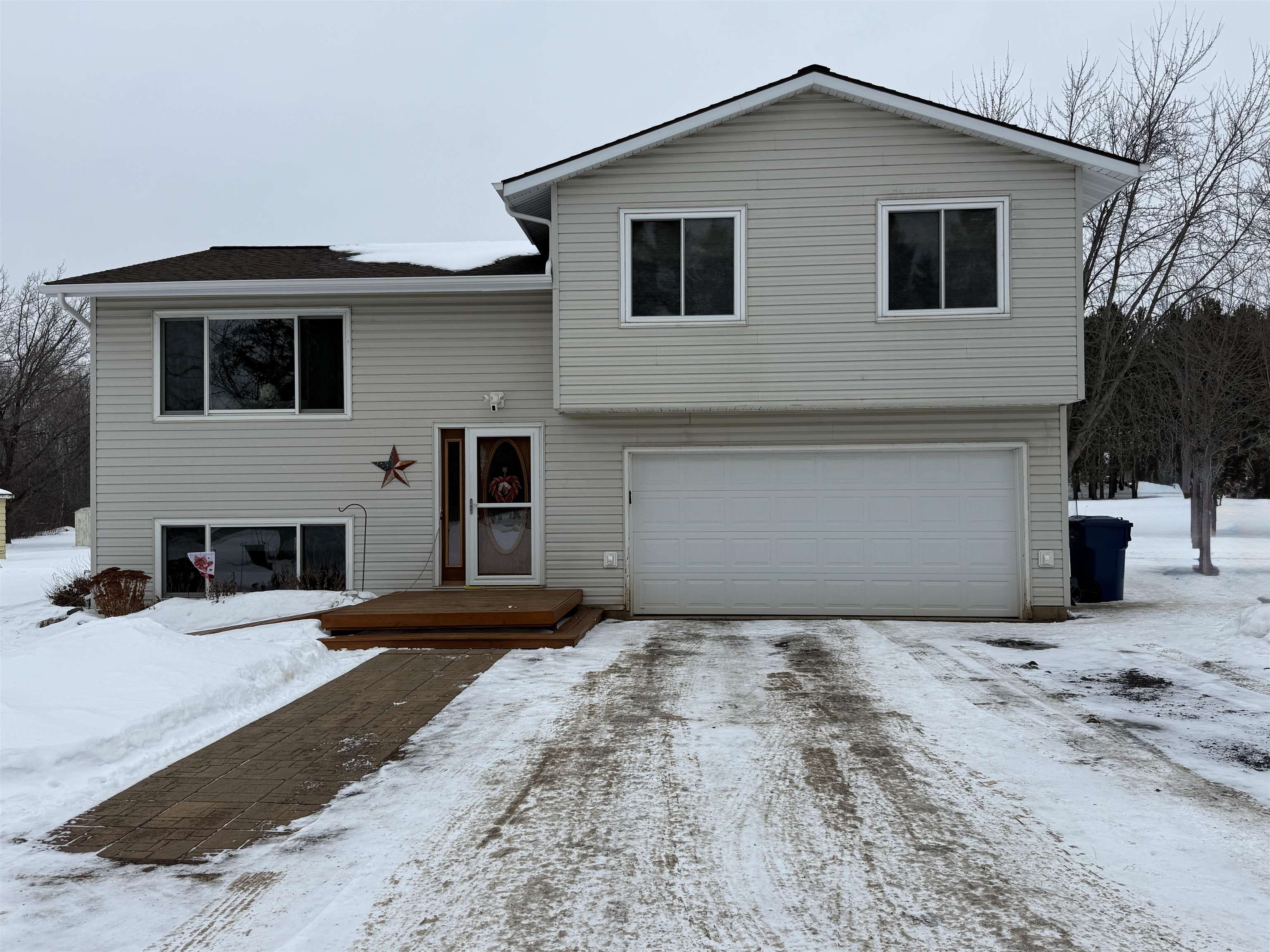 View of front of property featuring an attached garage, a deck, and driveway