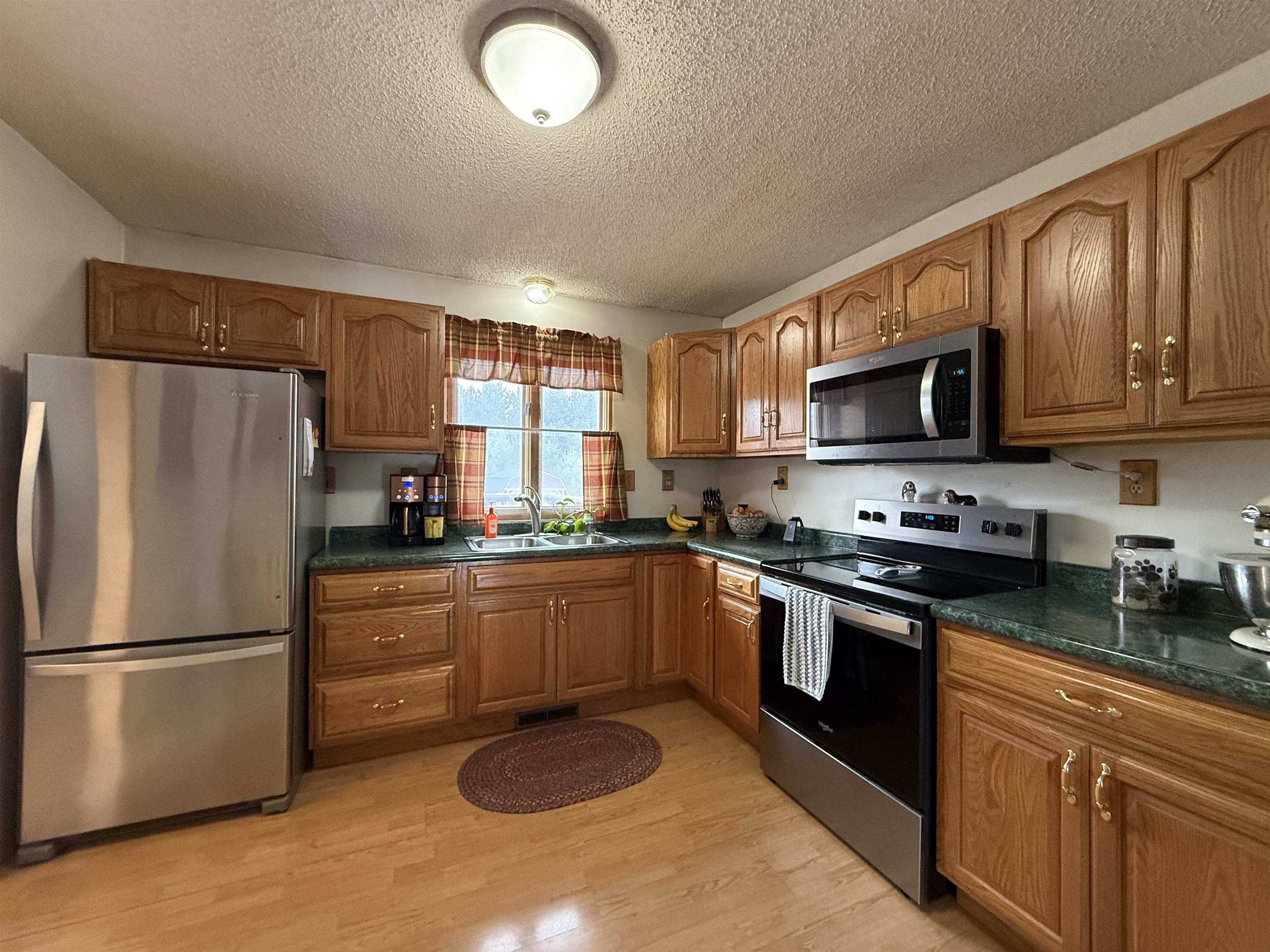 3991 Dillon Road Hibbing, MN 55746 - Photo 10 of 25 Kitchen with wood finish cabinetry, stainless steel appliances, a textured ceiling, and light wood-style floors