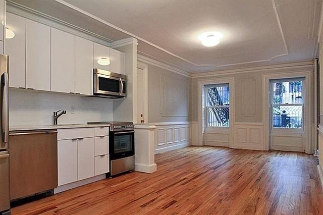 a kitchen with stainless steel appliances granite countertop a stove top oven a sink dishwasher and a microwave oven on the wooden floor