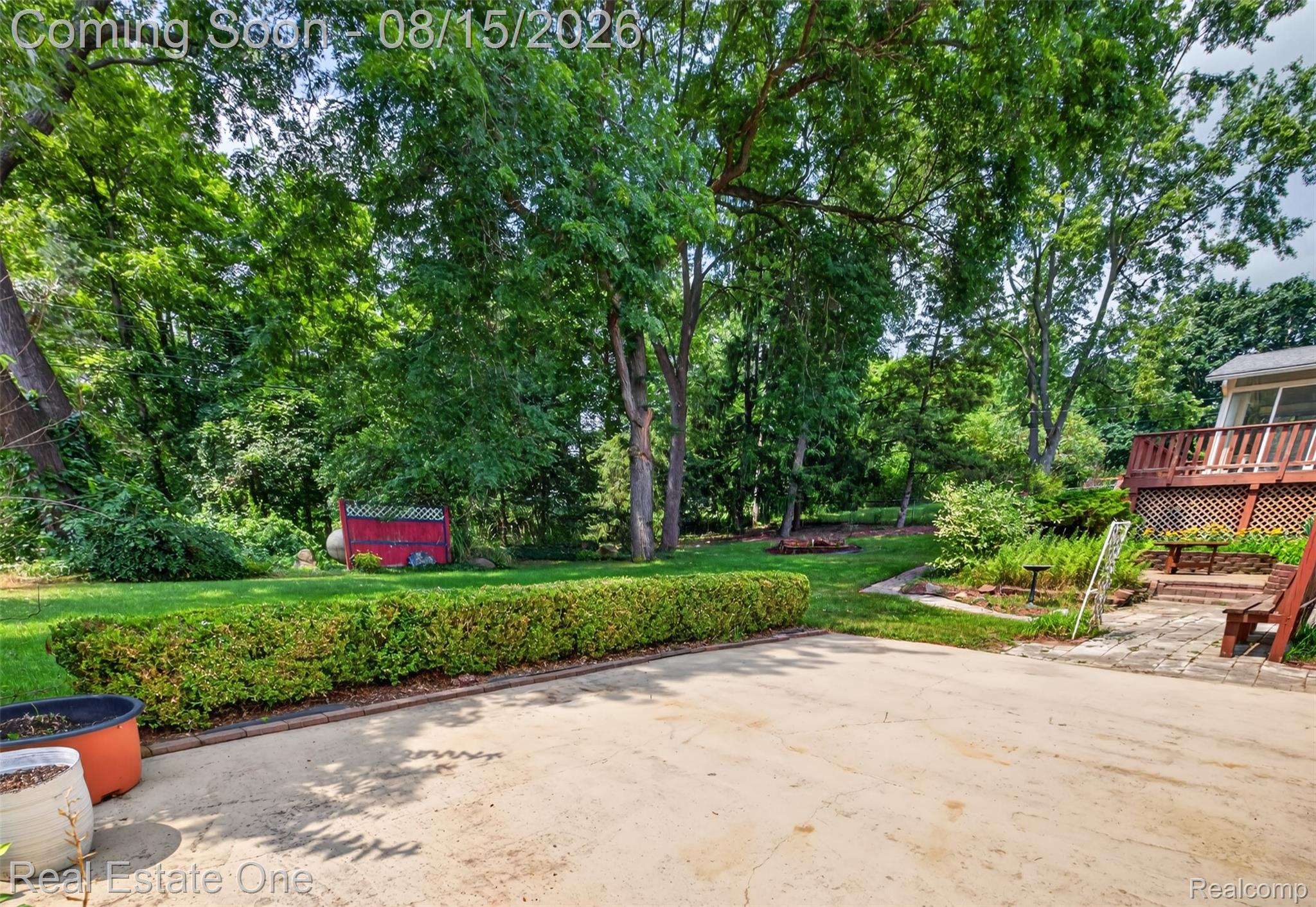 454 South Baldwin Road Oxford, MI 48371 - Photo 40 of 64 Expansive green space featuring mature trees, a red storage shed, a manicured hedge, and a multi-level wood deck with lattice accents