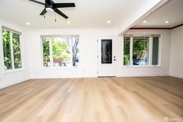 a view of an empty room with wooden floor and a window