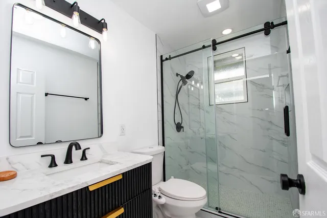 a bathroom with a granite countertop sink toilet mirror and shower