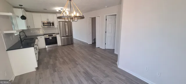 an empty room with wooden floor closet and windows