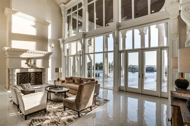 a living room with furniture a fireplace and floor to ceiling windows