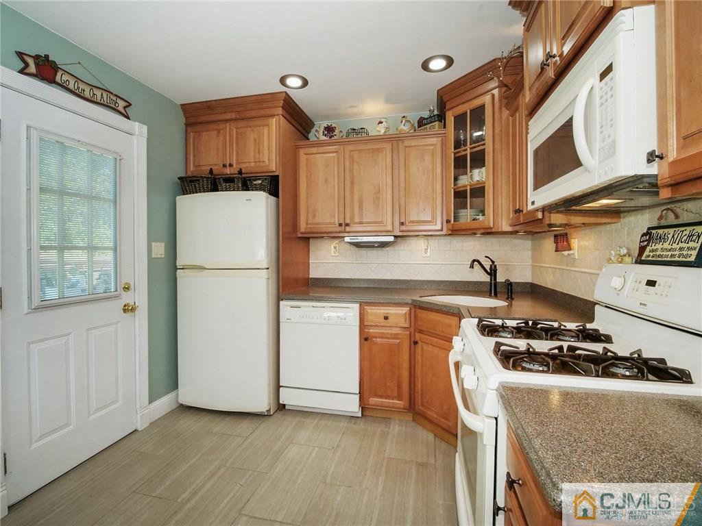 13 Stiles Road Edison, NJ 08817 - Photo 7 of 24 a kitchen with a refrigerator a stove a microwave and wooden cabinets
