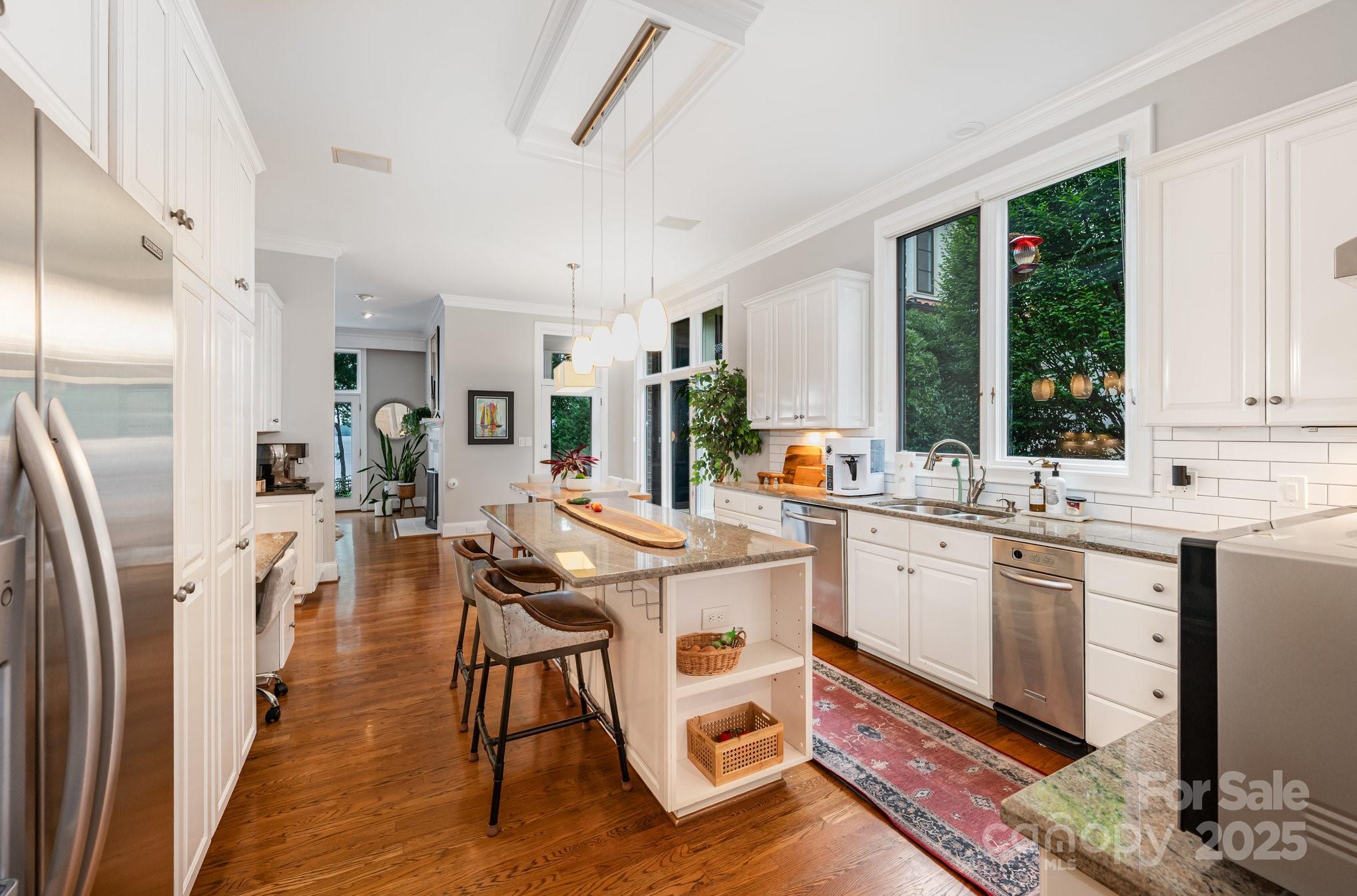 16133 North Point Road Huntersville, NC 28078 - Photo 19 of 48 a kitchen with stainless steel appliances kitchen island granite countertop a refrigerator a stove a sink dishwasher and white cabinets with wooden floor