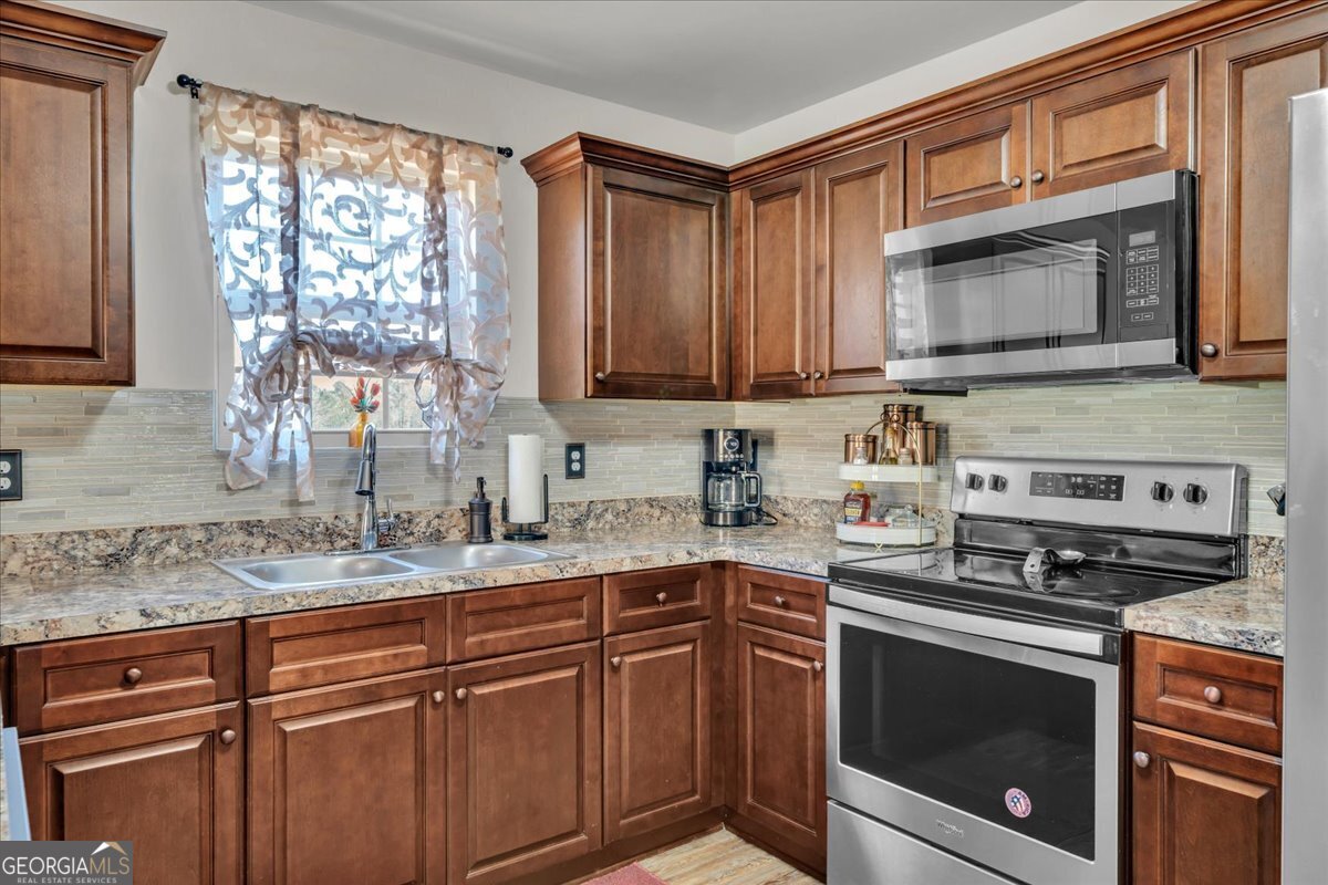 773 Weldon Road Forsyth, GA 31029 - Photo 11 of 37 a kitchen with granite countertop a sink cabinets stainless steel appliances and a window