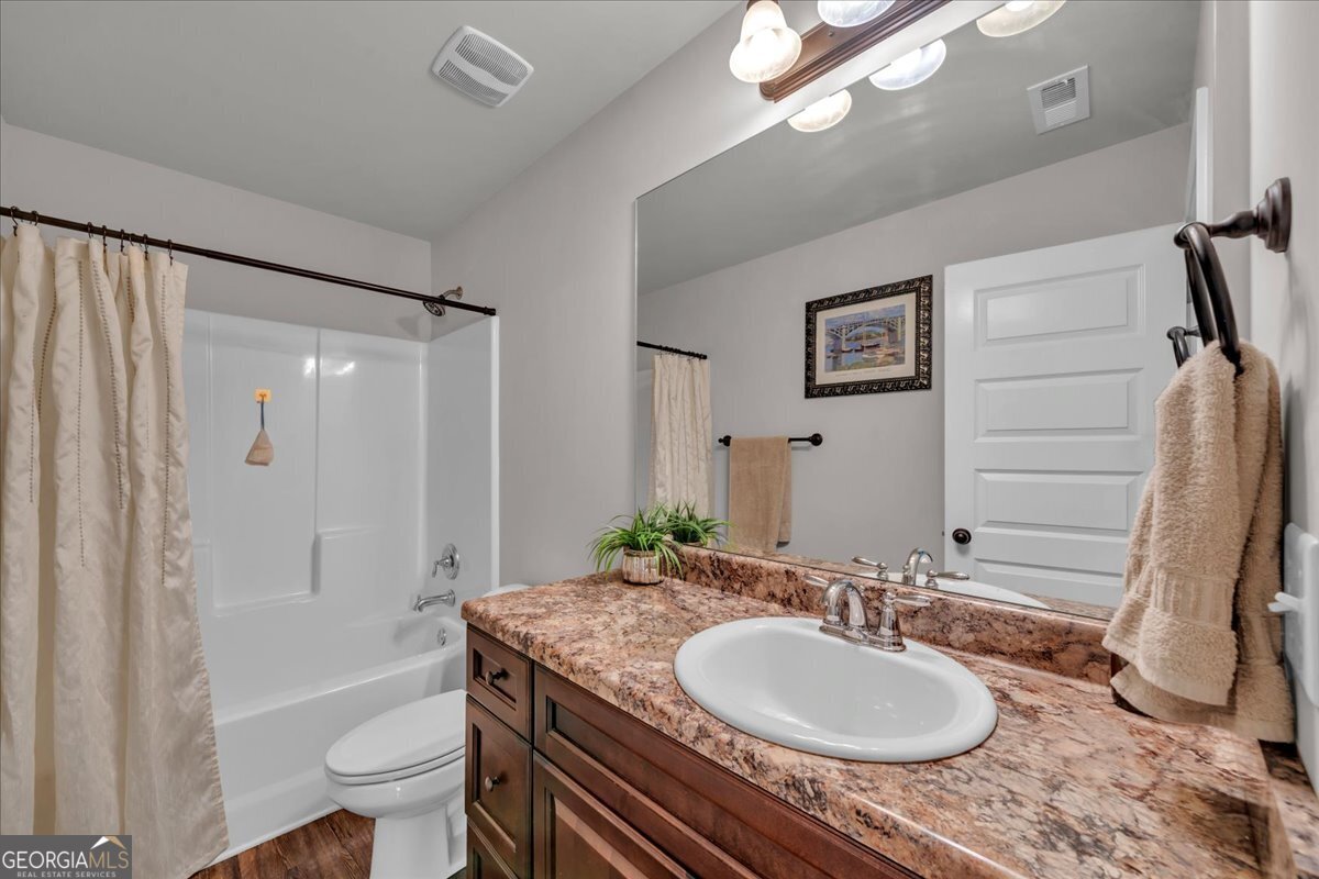 773 Weldon Road Forsyth, GA 31029 - Photo 23 of 37 a bathroom with a granite countertop sink a toilet a mirror and shower