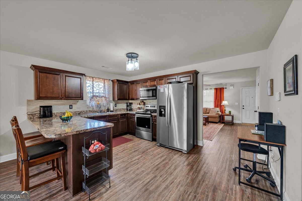 773 Weldon Road Forsyth, GA 31029 - Photo 9 of 37 a open kitchen with stainless steel appliances granite countertop a refrigerator stove top oven dining table and chairs