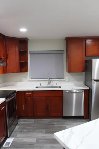 a large kitchen with stainless steel appliances wooden cabinets and a counter top space