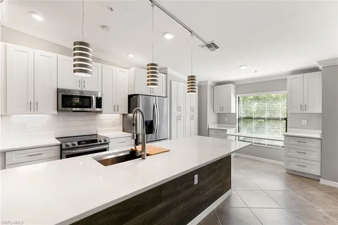 a kitchen with a refrigerator a stove and white cabinets with wooden floor