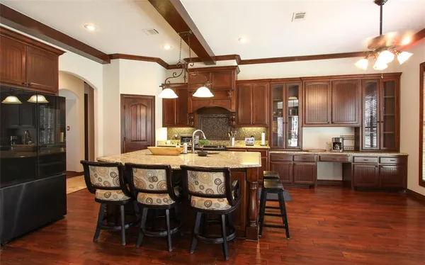 a kitchen with stainless steel appliances kitchen island granite countertop a table chairs and wooden floor