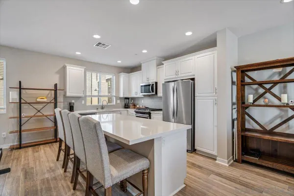 a kitchen with stainless steel appliances granite countertop a refrigerator a stove a sink dishwasher and a dining table with wooden floor