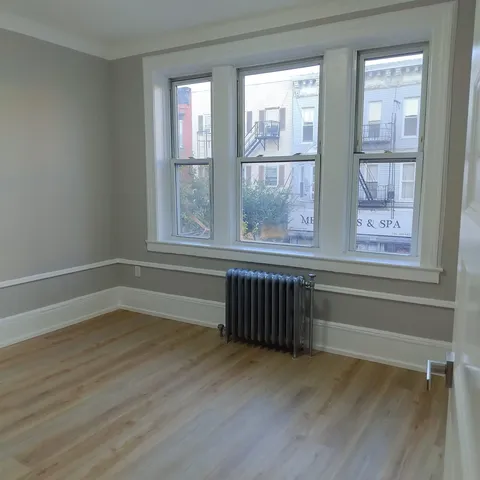a view of an empty room with wooden floor and a window