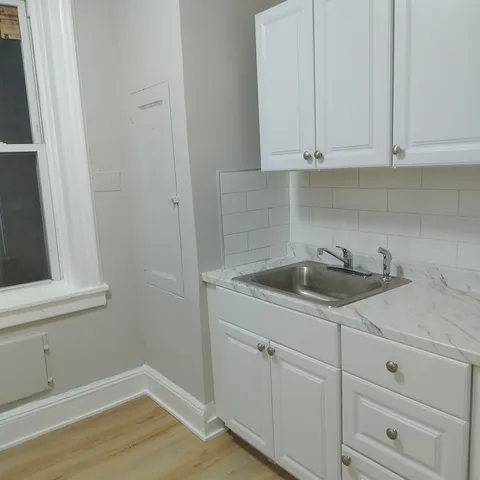a kitchen with white cabinets and sink