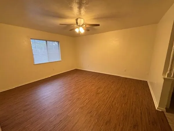 a view of an empty room with wooden floor and a window