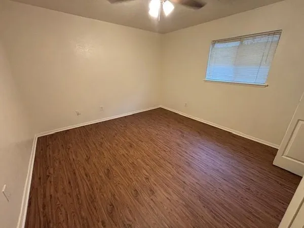 a view of an empty room with wooden floor and a chandelier