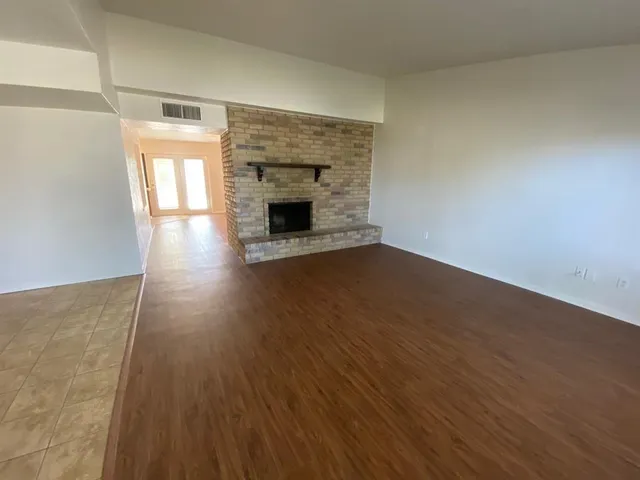 a view of empty room with wooden floor and fireplace
