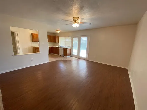 a view of an empty room with wooden floor and a window