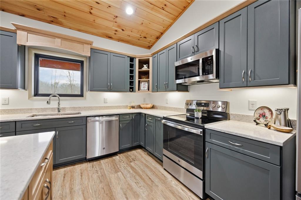 1581 Taylor Town Road Northeast Ranger, GA 30734 - Photo 6 of 30 a kitchen with stainless steel appliances granite countertop a sink dishwasher stove and microwave with wooden cabinets