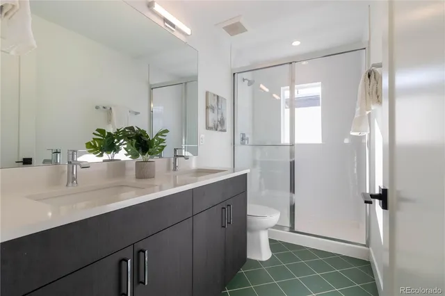 a bathroom with a double vanity sink toilet and a tub