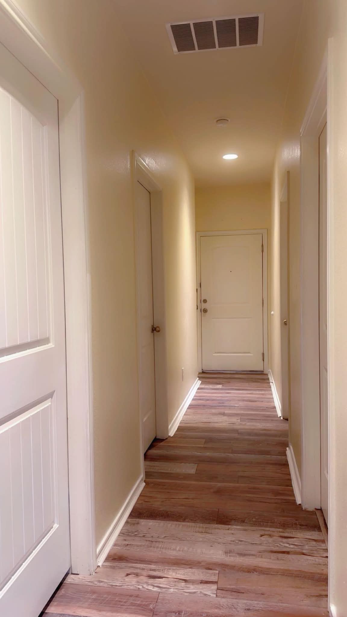 13004 Tinker Street Manor, TX 78653 - Photo 5 of 9 Navigate through this well-lit hallway featuring robust hardwood flooring and bright white trim.