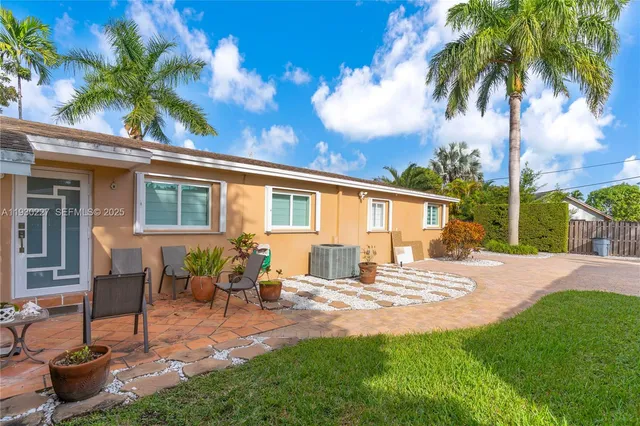 a view of a backyard with table and chairs potted plants and palm tree