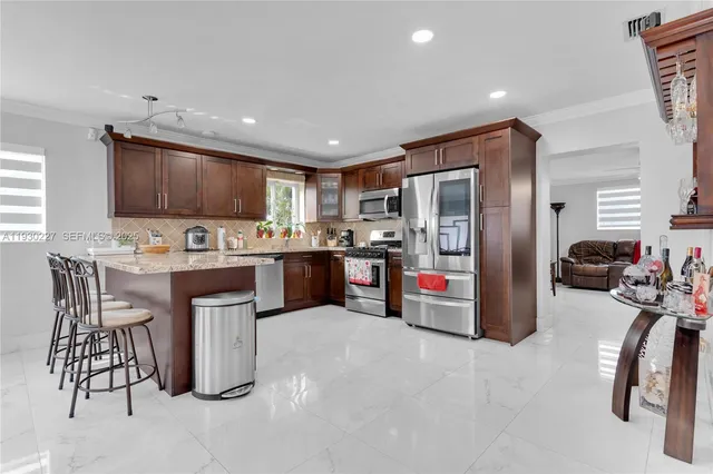 a kitchen with stainless steel appliances kitchen island granite countertop a refrigerator and a stove top oven