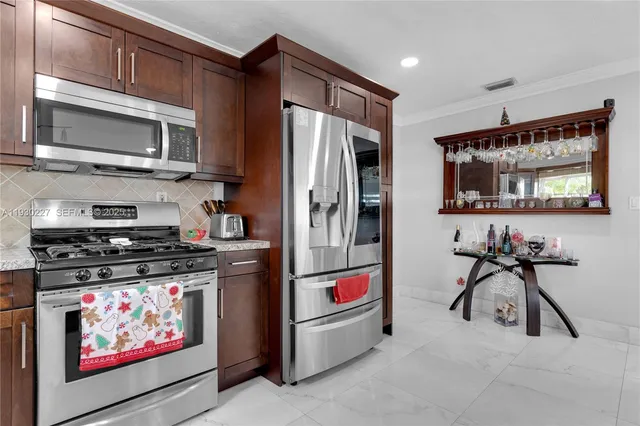 a kitchen with stainless steel appliances kitchen island granite countertop a refrigerator and a stove top oven
