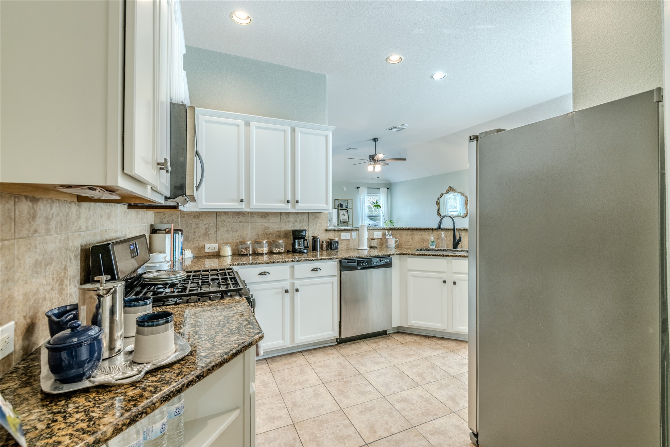 1089 Hot Spring Valley Buda, TX 78610 - Photo 6 of 26 Gleaming granite countertops pair beautifully with white cabinetry and durable tile flooring.