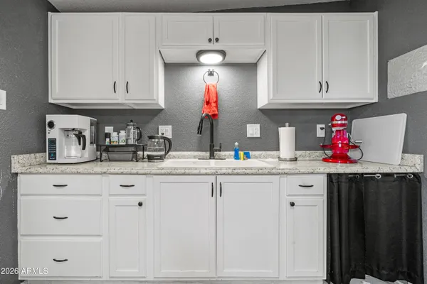 a kitchen with white cabinets and sink