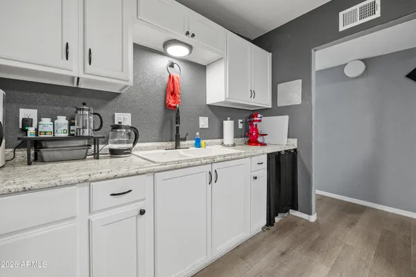 a kitchen with granite countertop a sink cabinets and wooden floor