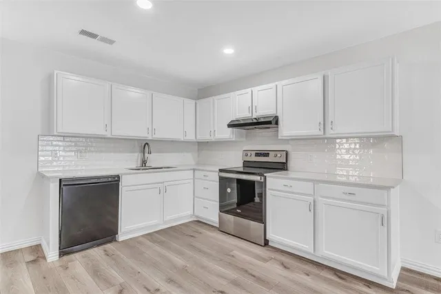 a kitchen with stainless steel appliances granite countertop a stove and white cabinets