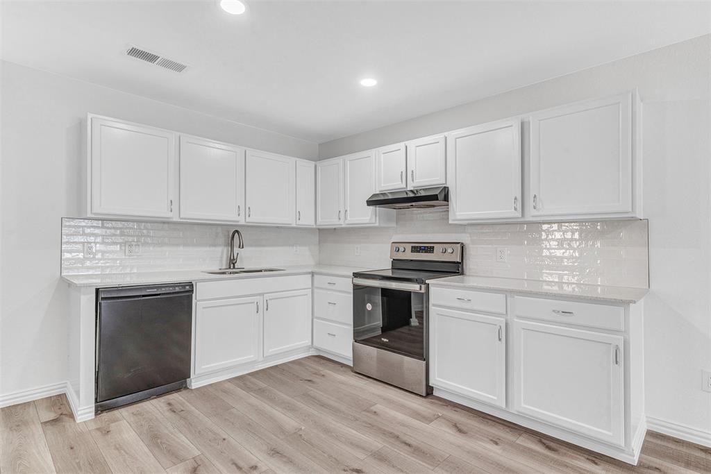 a kitchen with stainless steel appliances granite countertop a stove and white cabinets