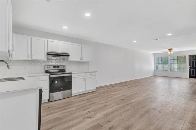 a kitchen with granite countertop a stove a sink and a refrigerator