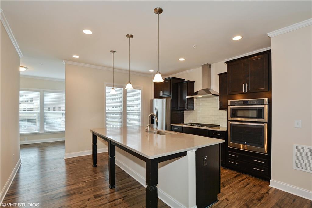 200 Braeden Way Alpharetta, GA 30009 - Photo 5 of 52 a kitchen with kitchen island a sink stainless steel appliances and wooden floor