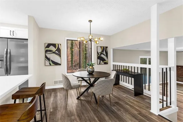 a kitchen with stainless steel appliances kitchen island granite countertop a table chairs and a refrigerator
