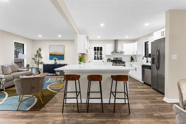 a kitchen with white cabinets stainless steel appliances and wooden floor