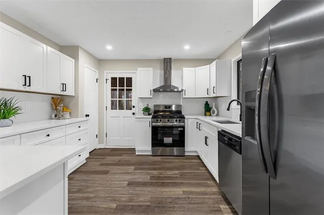 a kitchen with white cabinets and wooden floors