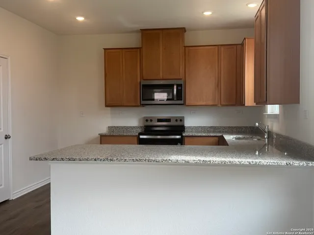 a kitchen with granite countertop a sink a stove a microwave and wooden cabinets