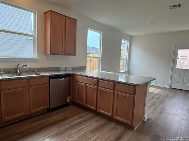 a kitchen with stainless steel appliances granite countertop wooden cabinets a sink and dishwasher with wooden floor