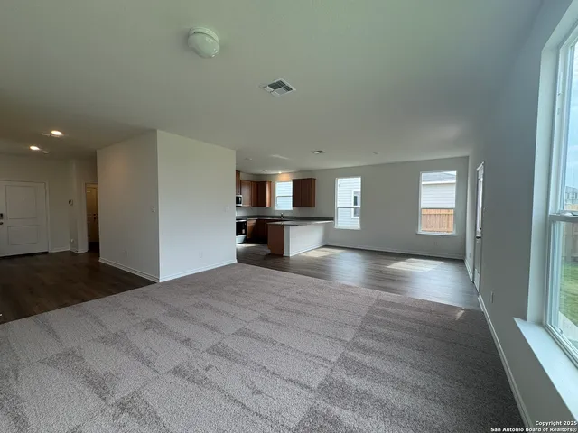 a view of empty room with kitchen and window