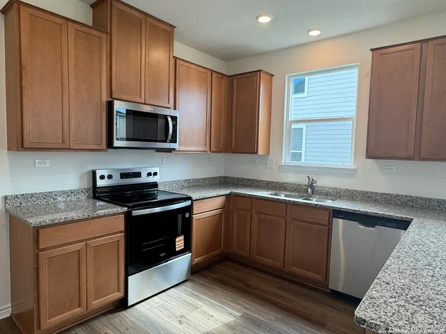 a kitchen with stainless steel appliances granite countertop wooden cabinets stove top oven and sink