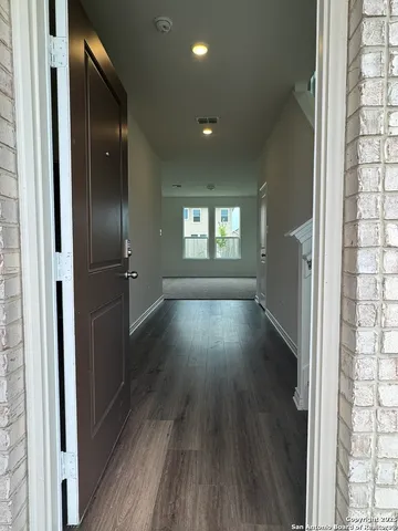a view of hallway with wooden floor and a window