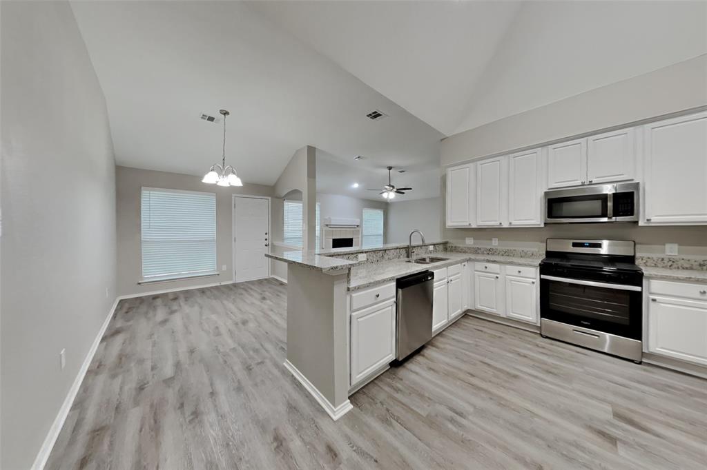 817 Fox Hunt Trail Fort Worth, TX 76179 - Photo 16 of 17 Kitchen featuring appliances with stainless steel finishes, a chandelier, white cabinetry, open floor plan, and hanging light fixtures