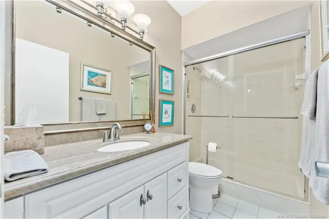 a bathroom with a granite countertop sink toilet a mirror and shower