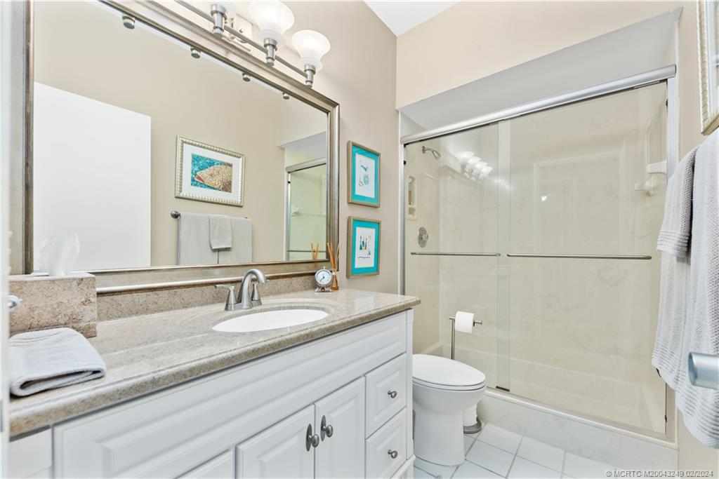 13424 Harbour Ridge Boulevard, Unit 4A Palm City, FL 34990 - Photo 22 of 33 a bathroom with a granite countertop sink toilet a mirror and shower