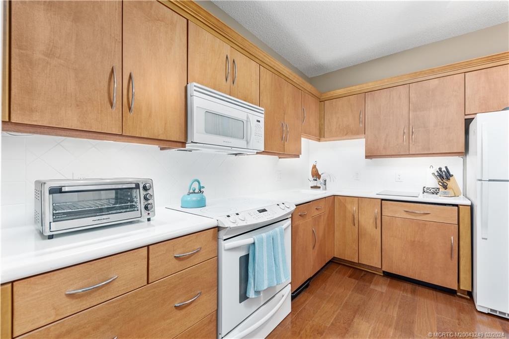 13424 Harbour Ridge Boulevard, Unit 4A Palm City, FL 34990 - Photo 8 of 33 a kitchen with stainless steel appliances granite countertop wooden cabinets a stove a sink and dishwasher with wooden floor